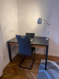 a desk with a blue chair and a laptop on it at Maros Apartman in Budapest