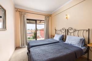1 dormitorio con 2 camas y ventana grande en Marietta's Resort by Konnect, Gouvia Corfu en Gouvia