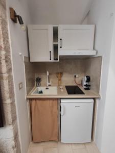 una pequeña cocina con armarios blancos y fregadero en Archi Antichi, en Putignano