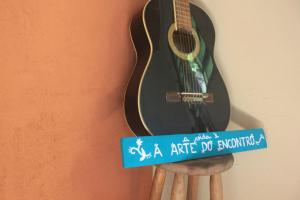 a guitar hanging on a wall with a sign at Refúgio na Natureza - Recanto Leve Amor in Águas de Lindóia