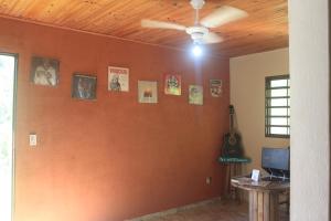 a living room with an orange wall with pictures on it at Refúgio na Natureza - Recanto Leve Amor in Águas de Lindóia