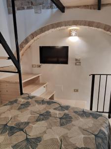 a bedroom with a bed and a flat screen tv at Archi Antichi in Putignano