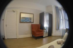 a living room with a chair and a mirror at Kensington Guest House Liverpool in Liverpool