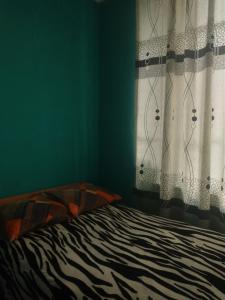 1 dormitorio con 1 cama con cortina y ventana en Hospedaje Akankma en Juliaca