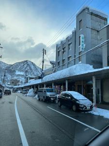a snowy street with cars parked on the side of the road at 駅本ビル民宿 in Yuzawa