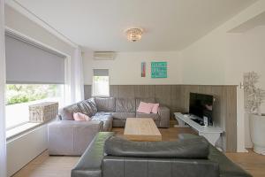a living room with a couch and a table at Villa Pakhuys - groepsaccommodatie - Julianadorp aan Zee in Den Helder