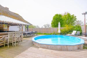 una piscina con sillas, una mesa y un patio en Villa Pakhuys - groepsaccommodatie - Julianadorp aan Zee, en Den Helder