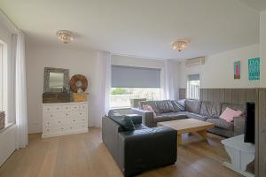 uma sala de estar com um sofá e uma mesa em Villa Pakhuys - groepsaccommodatie - Julianadorp aan Zee em Den Helder
