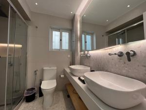 een badkamer met een wastafel, een toilet en een spiegel bij VoulaCnSand in Athene