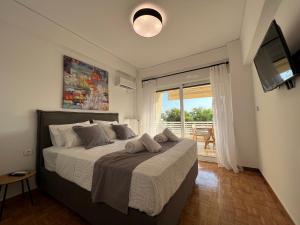 a bedroom with a bed with a television and a balcony at VoulaCnSand in Athens