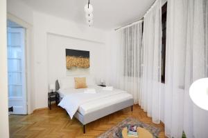 a white bedroom with a bed and a window at Caragiale Apartment in Bucharest