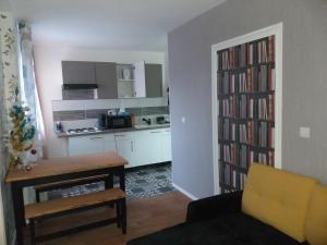 a kitchen and a living room with a table and a book shelf at Joli petit appartement in Charleville-Mézières