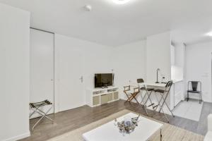 Una sala de estar blanca con una mesa y un televisor. en Chic studio Appartment, en Rosny-sous-Bois