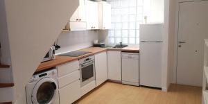 a kitchen with white cabinets and a washer and dryer at Somo Playa Vistas in Somo