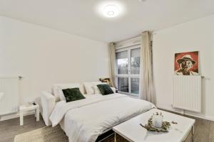 ein weißes Schlafzimmer mit einem Bett und einem Tisch in der Unterkunft Chic studio Appartment in Rosny-sous-Bois