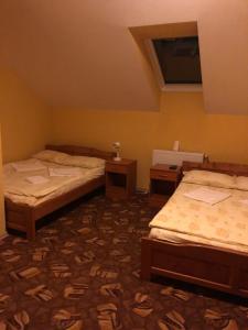 two beds in a room with two tables at H&T Pension-Restaurant in Jigodinu