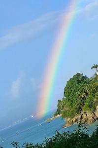 a rainbow in the sky over a body of water at Studio AQUA à GOSIER in Le Gosier