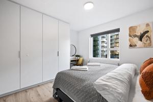 a white bedroom with a bed and a window at Venture Vacations - Unwind in Luxury Steps From Smáralind Mall in Reykjavík