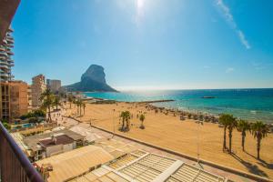 a view of a beach with palm trees and the ocean at Apartamento Calpeplaya - PlusHolidays in Calpe