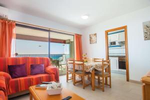 a living room with a red couch and a table at Apartamento Calpeplaya - PlusHolidays in Calpe