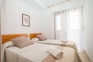 two beds in a white room with a window at Apartamento Calpeplaya - PlusHolidays in Calpe
