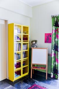 ein gelbes Bücherregal mit einem Whiteboard in einem Zimmer in der Unterkunft Colourful Apt in Nea Smyrni in Athen