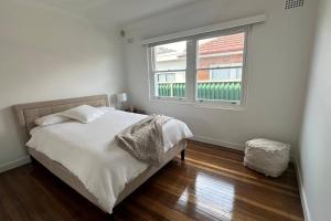 a white bedroom with a bed and a window at Delightful Home with Amazing city views! in Sydney