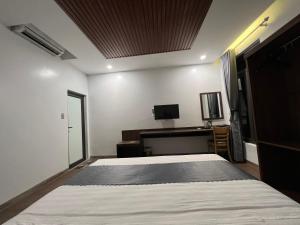 Schlafzimmer mit einem Bett, einem Schreibtisch und einem TV in der Unterkunft Happy House Moc Chau in Mộc Châu