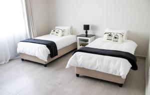 1 dormitorio con 2 camas con sábanas blancas y negras en Asania Guest House en Bloemfontein