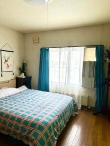 een slaapkamer met een bed met blauwe gordijnen en een raam bij PENSION YunShuiYao雲水瑶民宿 in Furano