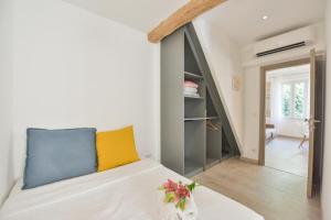a room with a bed with a yellow and blue pillow at LE PETIT CASTELET - New superb flat in old Antibes, AC, WIFI, for 4 in Antibes