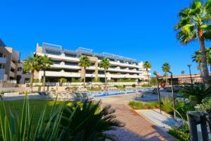 a large building with palm trees and a swimming pool at Flamenca Village south facing close to the beach (VDE-045) in Orihuela