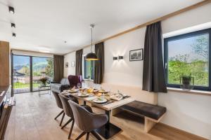 Emma Deluxe Aparthotel direkt beim Skibus في بيسندورف: غرفة طعام وغرفة معيشة مع طاولة وكراسي