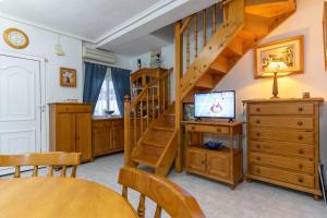 uma sala de estar com uma escada de madeira e uma televisão em rentafive Nuevo AA Admite Perros Barbacoa em Santa Pola