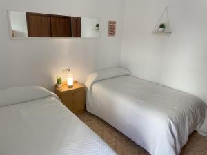 two beds in a bedroom with a candle on a night stand at Piso compartido Delyrent, Safa in Jaén
