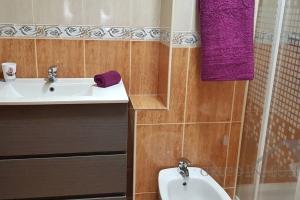 y baño con lavabo, aseo y toallas púrpuras. en Ático del sol, en Fuengirola 15 fotos más