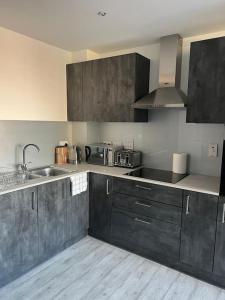 uma cozinha com armários cinzentos e um lavatório de aço inoxidável em Stylish Luxury new 2 bedroom Apartment em Dartford