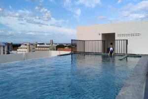 uma criança sentada à beira de uma piscina num edifício em The Base Hua Hin em Hua Hin