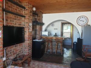 a room with a brick wall with a bar and a tv at Serendipity self catering one bedroom apartment in Despatch