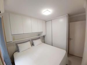 Apartamento Aconchegante في فوز دو إيغواسو: غرفة نوم صغيرة مع سرير أبيض ودواليب بيضاء
