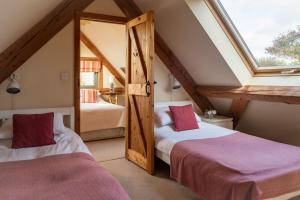 a attic room with two beds and a window at The Nook in Holbeton