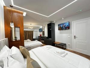 a hotel room with two beds and a tv on the wall at Vila Lordev in Korçë
