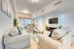 a living room with white furniture and a flat screen tv at Direct Access to Nakheel Mall At the Heart of The Palm in Dubai