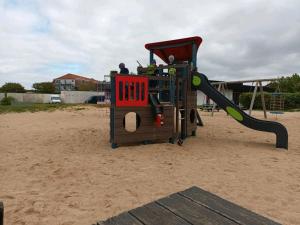 a playground with a slide in the sand at schöne Ferienwohnung in Friedrichskoog-Spitze in Friedrichskoog-Spitze