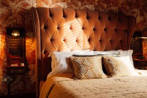uma cama com uma grande cabeceira acolchoada e almofadas em The George & Heart House em Kent