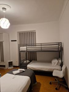 sypialnia z 2 łóżkami piętrowymi i krzesłem w obiekcie Zuni Guest House w Lizbonie