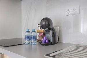 a kitchen counter with a coffee maker and bottles of water at Magnifique Studio Clichy in Clichy