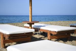 three lounge chairs and an umbrella on the beach at Nostos Beachfront Apartments & Studios in Agios Ioannis