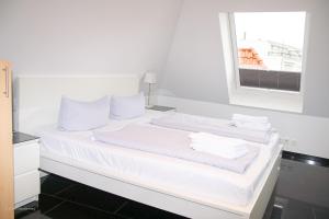 a white bed with white pillows and a window at SüdWind, Haus Portscher in Norderney