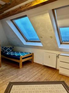 a attic room with a bed and two windows at An der Linde in Kall